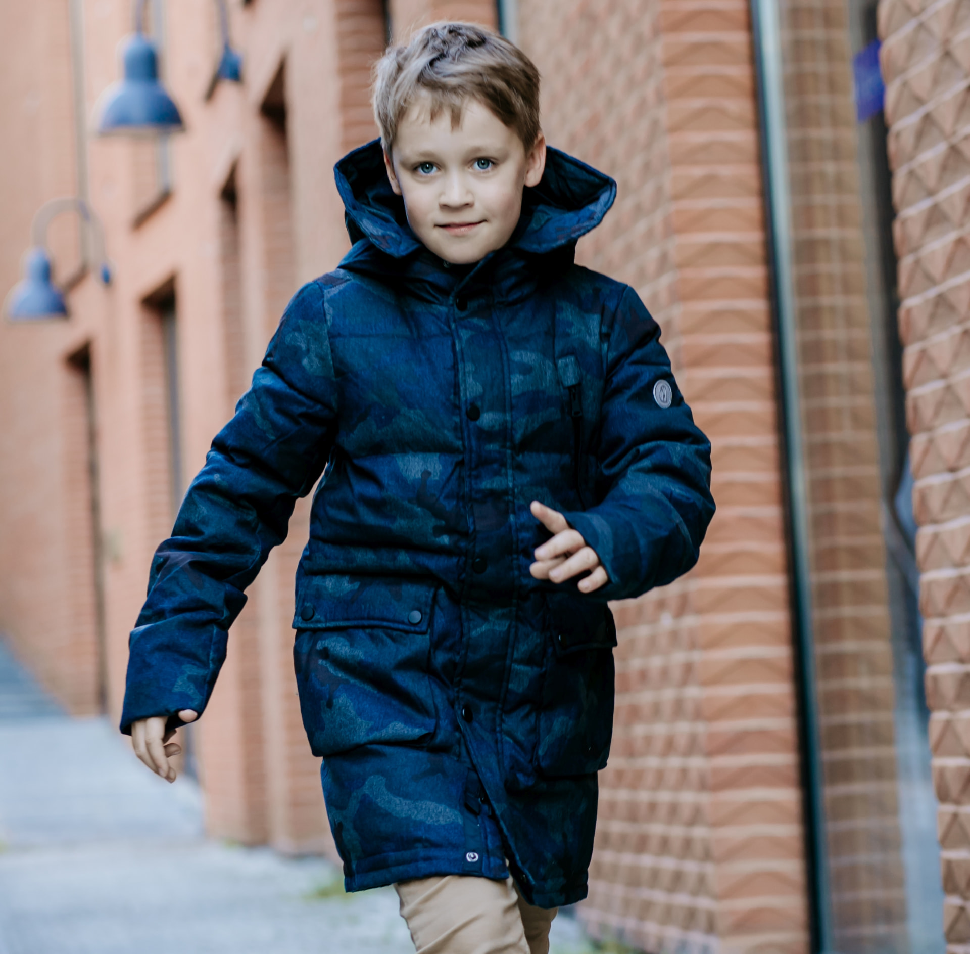 A boy wearing the Pengu KIDS Daiki down parka in camouflage blue